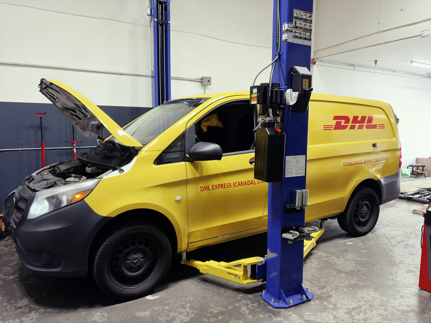 DHL delivery Mercedes Metris van on the lift for timing chain service