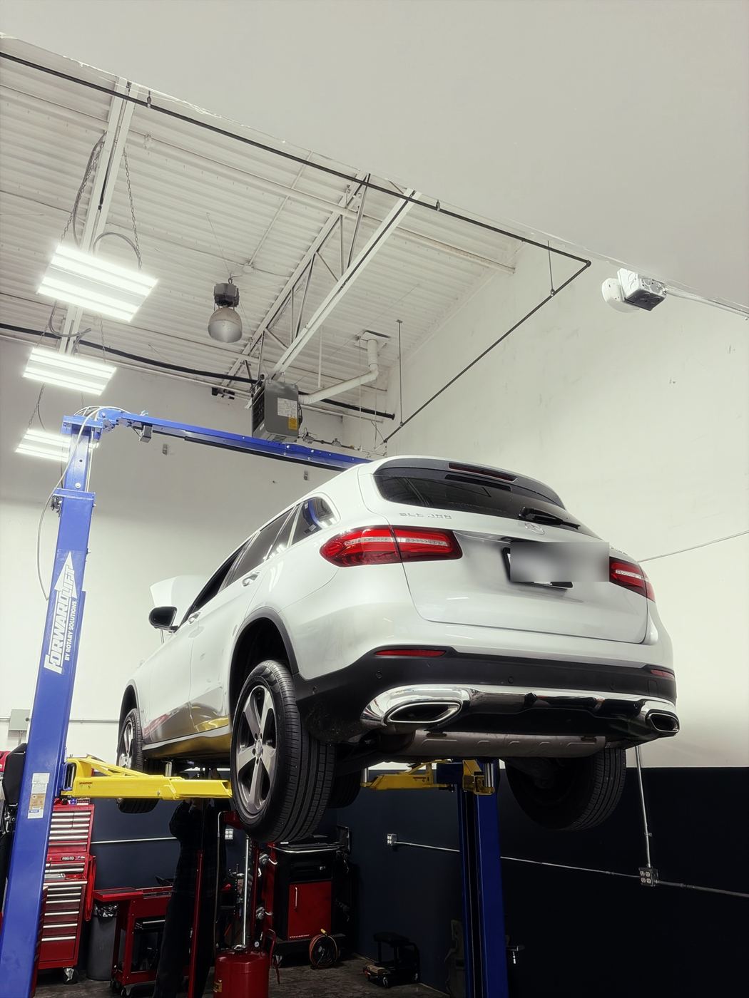 White Mercedes GLC300 on a two-post lift in the shop for diagnosis of an oil pump control valve fault